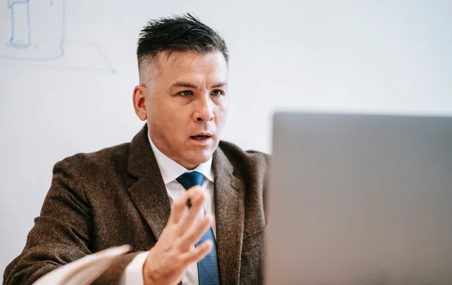 Professional businessman in formal attire engaged in an online meeting using a laptop. Checking account access and ownership at handover